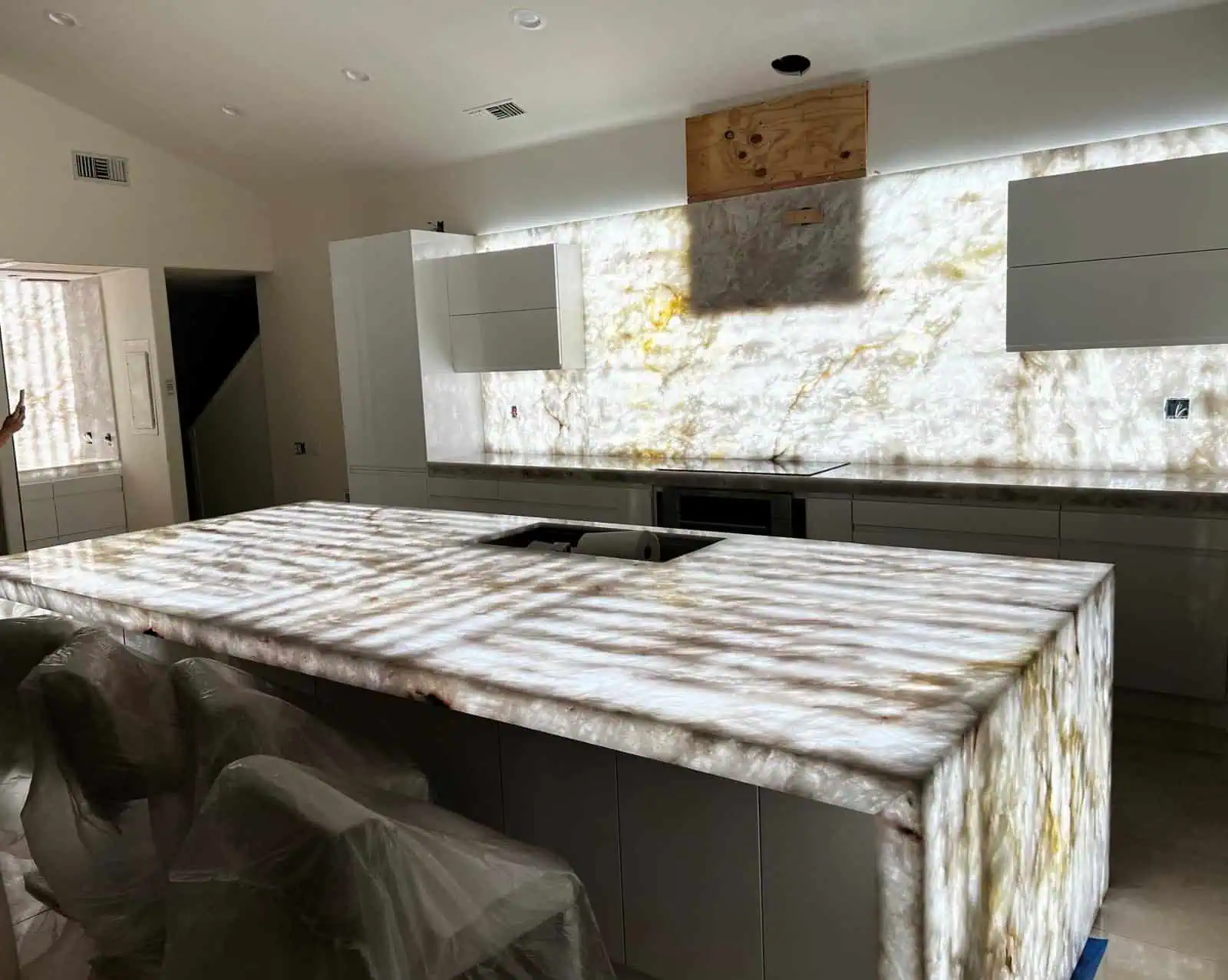 Luxurious onyx kitchen island with backlit onyx wall in modern kitchen.