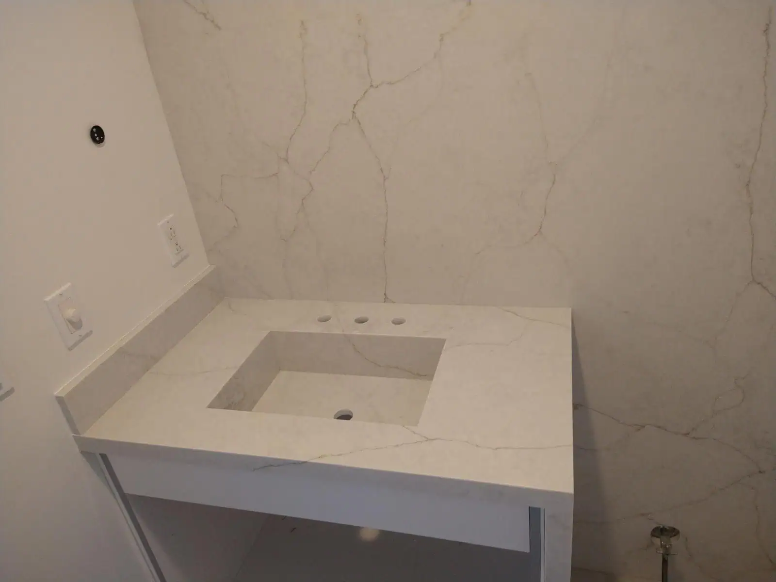 Marble bathroom vanity with integrated sink and wall-mounted faucet.