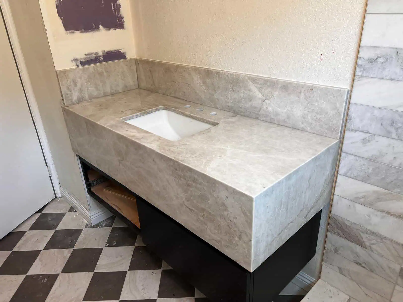 Contemporary marble bathroom vanity with integrated sink and black base.