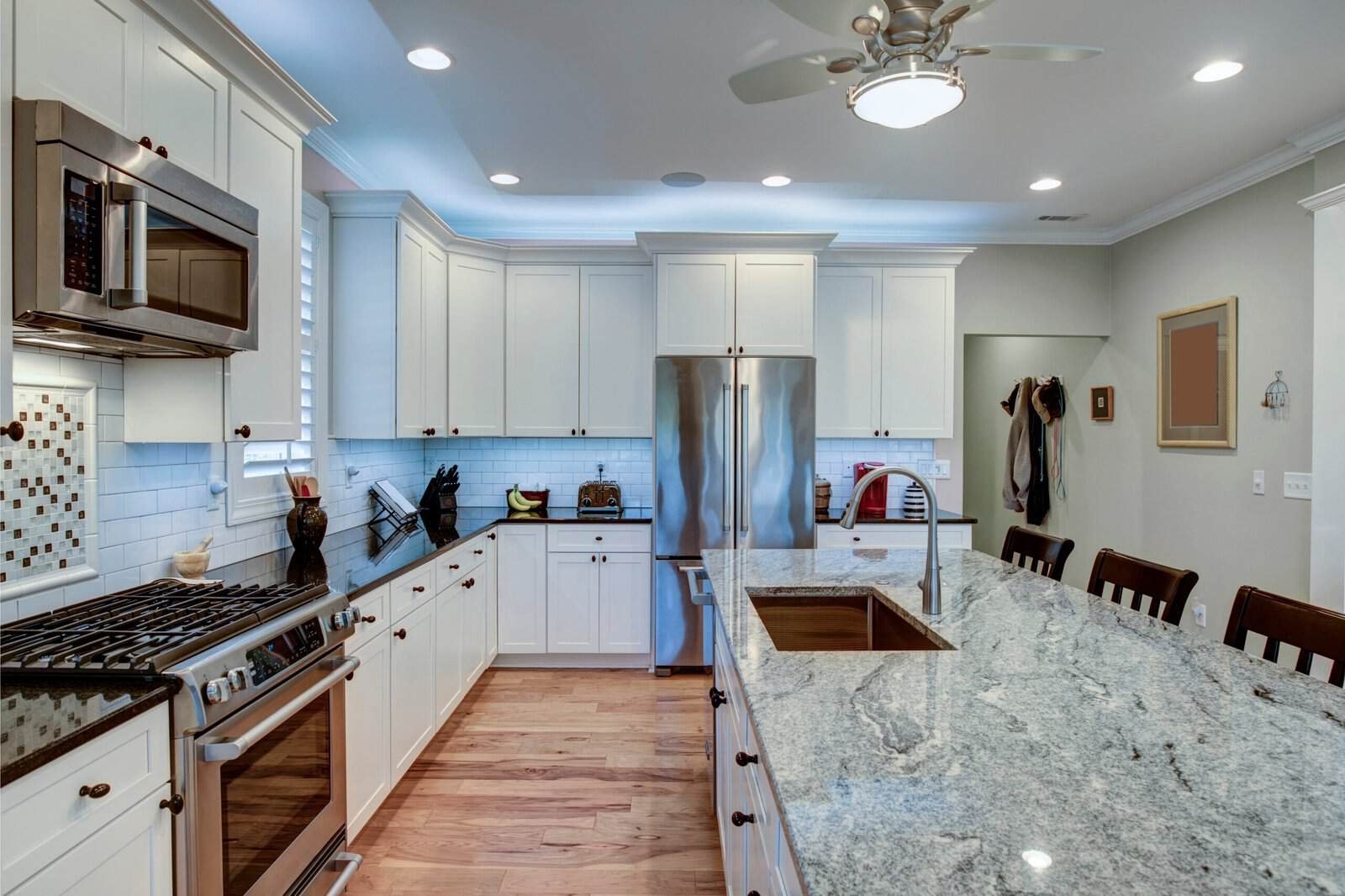 Bright modern kitchen with white cabinets and marble island countertop.